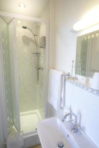 a white bathroom with a shower and a sink at Craignair Cottage in Dalbeattie