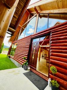 a wooden house with a large glass door at Cabana Dzsesszika&Erik in Kàszonuifalù