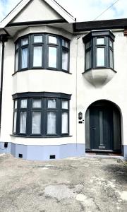 Biały dom z czarnymi oknami i podjazdem w obiekcie 4 Bed Family Home w mieście Woodford Green