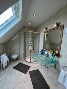 uma casa de banho com um lavatório de vidro e um chuveiro em ailleurs sous les etoiles em Manneville-la-Raoult