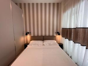 Bett in einem Zimmer mit gestreiften Wänden und Fenstern in der Unterkunft Casetta Celso in Rom