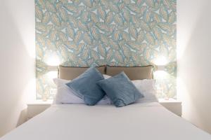 ein Bett mit zwei blauen Kissen und einer Wand in der Unterkunft Four Luxury Apartment in Palermo