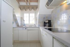 a white kitchen with a sink and a window at Syltnest-Munkmarsch in Munkmarsch