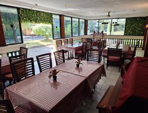 restauracja ze stołami, krzesłami i oknami w obiekcie Makati Pasuruan Hotel w mieście Pasuruan