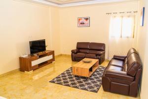 - un salon avec deux fauteuils en cuir et une télévision dans l'établissement Superbe appartement F4 à Dakar Mermoz-Sacré cœur, à Dakar