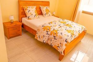 - une chambre avec un lit et une table avec une table de chevet dans l'établissement Superbe appartement F4 à Dakar Mermoz-Sacré cœur, à Dakar
