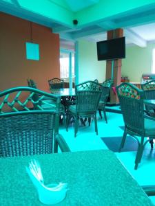 una sala da pranzo con tavoli, sedie e TV di Hotel Basilea Mtwapa a Mtwapa
