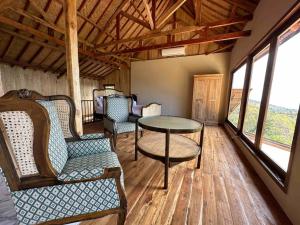 a living room with a table and chairs and windows at Hillside Chalet with panoramic views in Ambat
