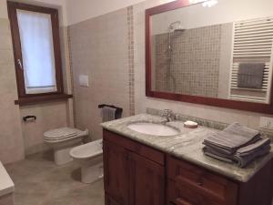 ein Badezimmer mit einem Waschbecken, einem WC und einem Spiegel in der Unterkunft APPARTAMENTO PIEVE ANTICA 