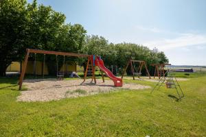 un parque infantil con un tobogán rojo y un columpio en srub slovenice, 