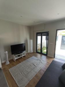 a living room with a flat screen tv and a rug at Casa Saudade in Charneca