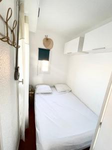 um pequeno quarto com uma cama branca em Studio de vacances 3eme et dernier étage vue Marina em Le Barcarès