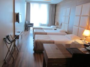 una camera d'albergo con quattro letti e una televisione di Derpa Hotel a Istanbul