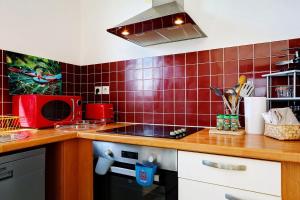 a kitchen with red tiles on the wall at La Terrasse - Apt T3 Saint Pierre in Saint-Pierre +27 photos