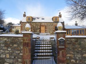 una casa de piedra con una puerta en la nieve en Silverstripe, en Turriff