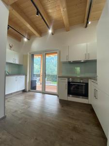 a large kitchen with white appliances and a wooden ceiling at Apart Montis in See