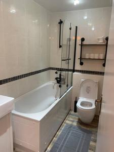 a bathroom with a white tub and a toilet at Cosy one bed flat free parking in Send