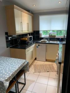 a kitchen with white cabinets and a table in it at Cosy one bed flat free parking in Send