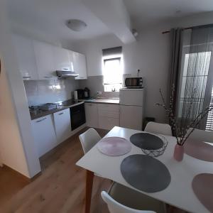 uma cozinha com uma mesa branca e cadeiras, uma mesa e uma sala de jantar em Apartments Filipovic em Biograd na Moru