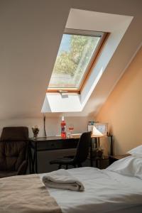 Schlafzimmer mit einem Fenster, einem Schreibtisch und einem Bett in der Unterkunft Diófa Panzió in Villány