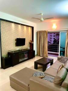 a living room with a couch and a flat screen tv at 3BHK Luxurious Apartment (AC/TV/Kitchen) in Mangalore