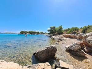 a beach with rocks and a boat in the water at Paradise kosirina in Murter
