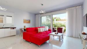 オルモス・パナギアスにあるAcrotel Porto Brava Luxury Villasの赤いソファとキッチンのあるリビングルーム