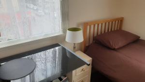 a bedroom with a bed and a table with a lamp at Upton Park - House in London