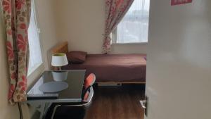 a small bedroom with a bed and a desk with a lamp at Upton Park - House in London