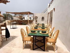 a long table with chairs on a patio at Villa Madame BABOUCHE - Maison Beldi avec piscine in Ghazoua