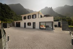 a large white house with mountains in the background at Casa Avô da Pedra, By OP in São Vicente