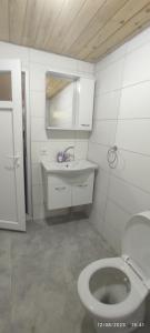 a white bathroom with a toilet and a sink at Teo Hotel in Cıralı