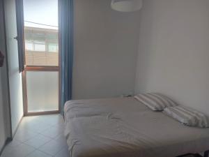 uma cama num quarto branco com uma janela em Casa Margherita em Deiva Marina