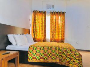 a bedroom with a bed with orange curtains at GRACE LODGE ONITSHA in Onitsha