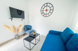 ein Wohnzimmer mit einem blauen Sofa und einer Uhr in der Unterkunft MISSYT DUPLEX COLOMBES PROCHE PARIS ET LA DÉFENSE in Colombes