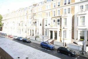 une rangée de voitures garées devant les bâtiments dans l'établissement Wonderful apartment in Earl’s Court, à Londres
