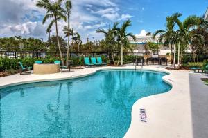 uma piscina com cadeiras azuis e palmeiras em Residence Inn Fort Lauderdale Pompano Beach Central em Pompano Beach