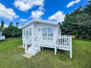a white tiny house on a grass field at Beautiful Lodge With Decking At Breydon Water Park In Norfolk Ref 10022b in Belton
