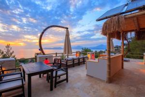 un patio con tavolo, sedie e ombrellone di Unique Sea View VILLA a Faralya Altre 20 foto