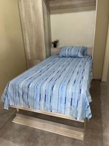 a bed with a blue and white comforter in a room at Casa camping san jerónimo in San Vicente de Cañete
