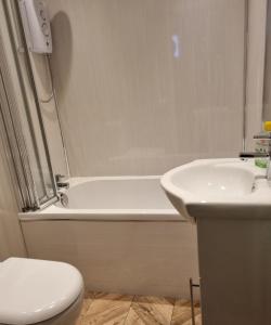 a bathroom with a tub and a toilet and a sink at Captivating 2-Bed ground floor Apartment in Largs in Largs