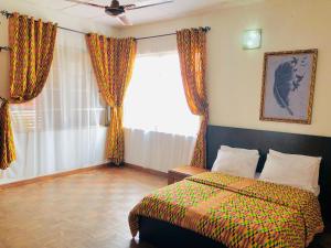 una camera da letto con un letto e una finestra con tende di GRACE LODGE ONITSHA a Onitsha