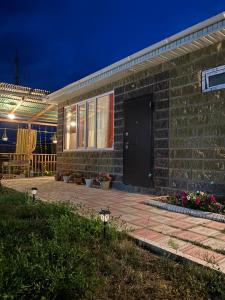 a brick house with a black door and a patio at Бэй Хаус ( The Bay Area) in Cholpon-Ata