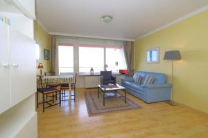 ein Wohnzimmer mit einem blauen Sofa und einem Tisch in der Unterkunft Haus am Meer. App 34 in Westerland