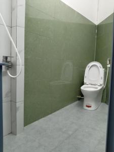 ein Badezimmer mit einem WC und einer grünen Wand in der Unterkunft NHÀ KHÁCH KEN in Cà Mau