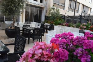 un patio con mesas, sillas y flores rosas en Torino Hotel Amman, en Amán