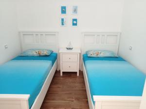 two beds in a room with white walls and wood floors at Casa Vacanze La Stella di Capo Blu in Santa Margherita di Pula