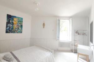 a white bedroom with a bed and a window at La Coquille in Sète