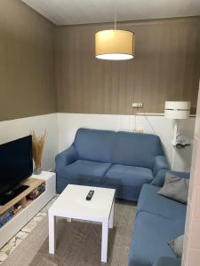 ein Wohnzimmer mit einem blauen Sofa und einem Tisch in der Unterkunft Casa Ameixeira in Carnota