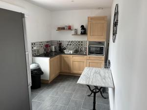 a kitchen with wooden cabinets and a tile floor at Jolie petite maison 4-6 couchages in Auchy-les-Mines